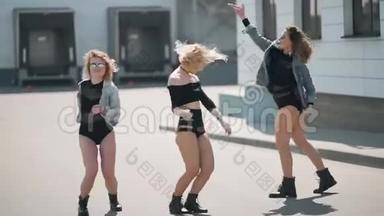 不同的三个女孩朋友在城市里穿着潮流牛仔裤享受乐趣和自由舞蹈。